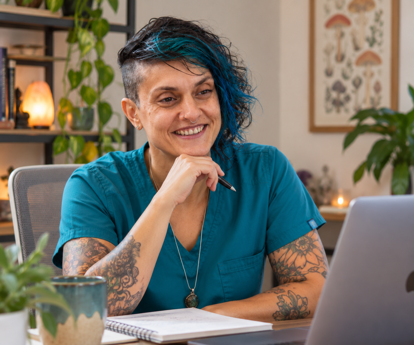 A registered nurse in teal scrubs smiling during a video call at her desk