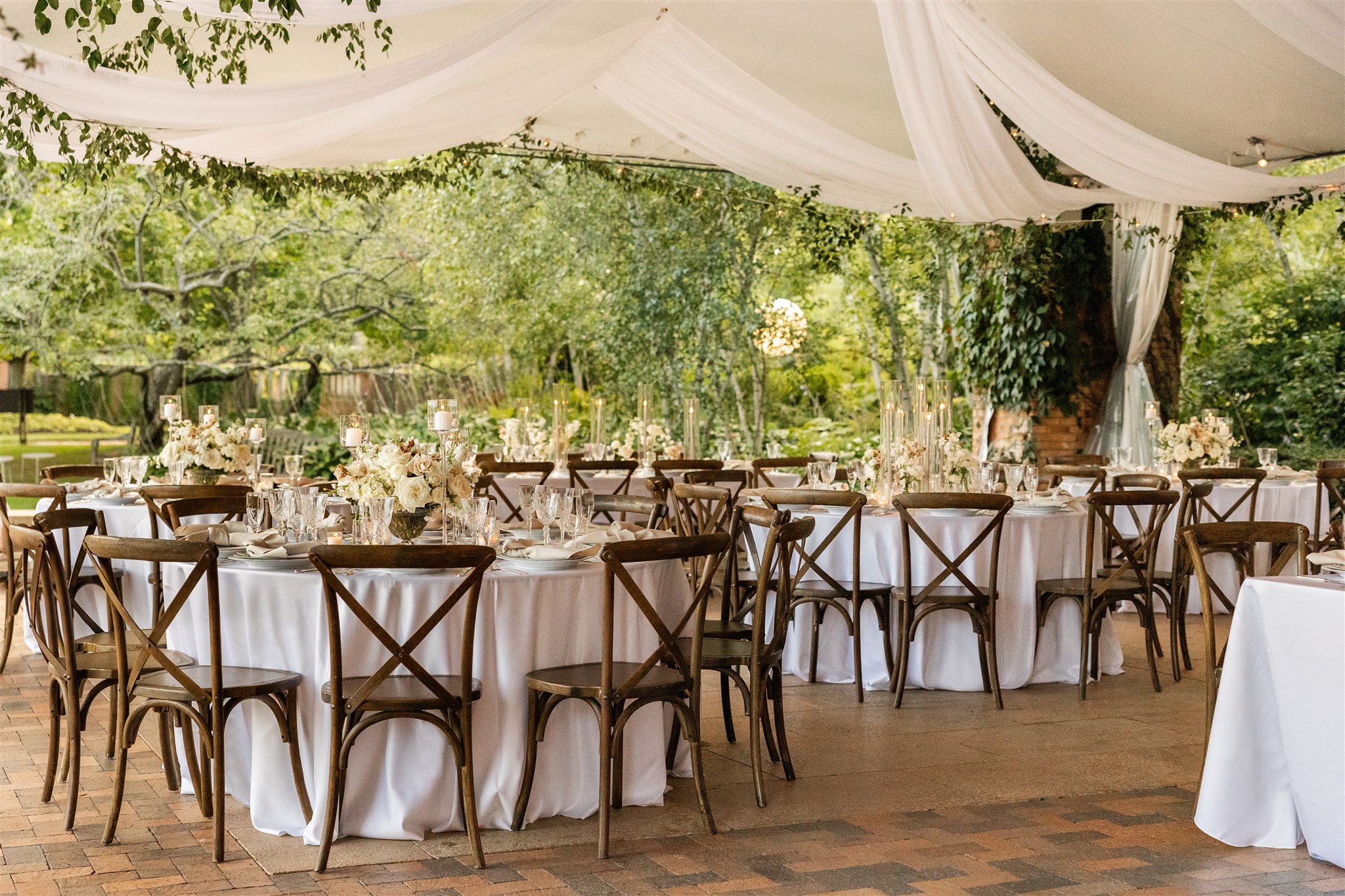 Tent reception tables with white florals and taper candles, planned by Michigan Avenue Events