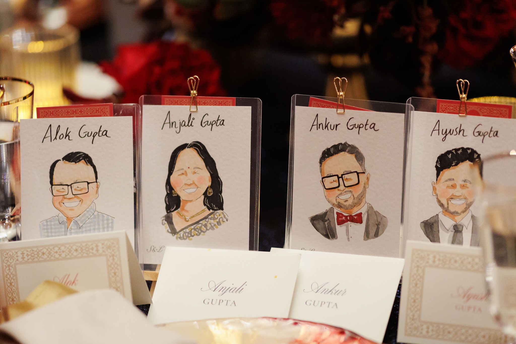 Hand-painted watercolor caricature place cards standing behind calligraphed name cards at a guest table