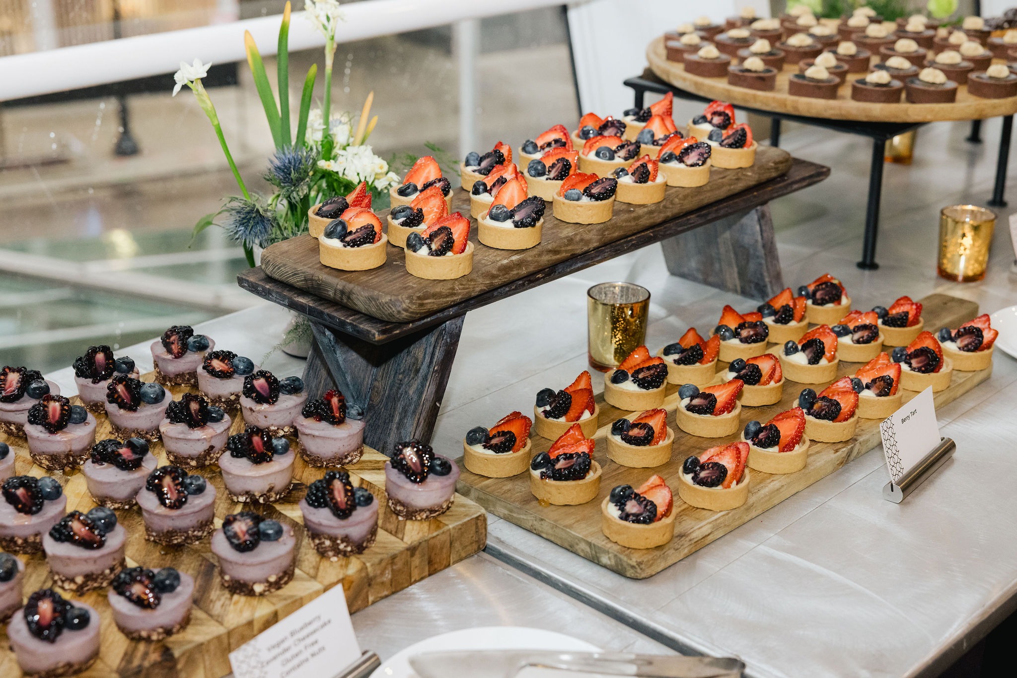 Dessert station with berry tarts and vegan blueberry lavender cheesecakes on wooden boards at the conference