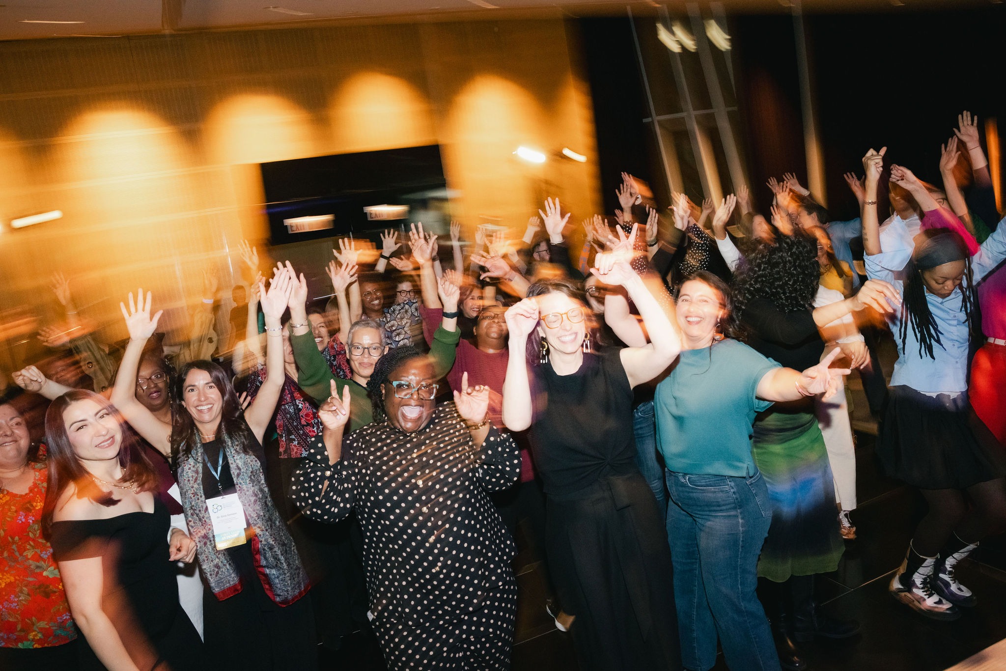 Conference attendees cheering with raised hands on the dance floor at the closing celebration