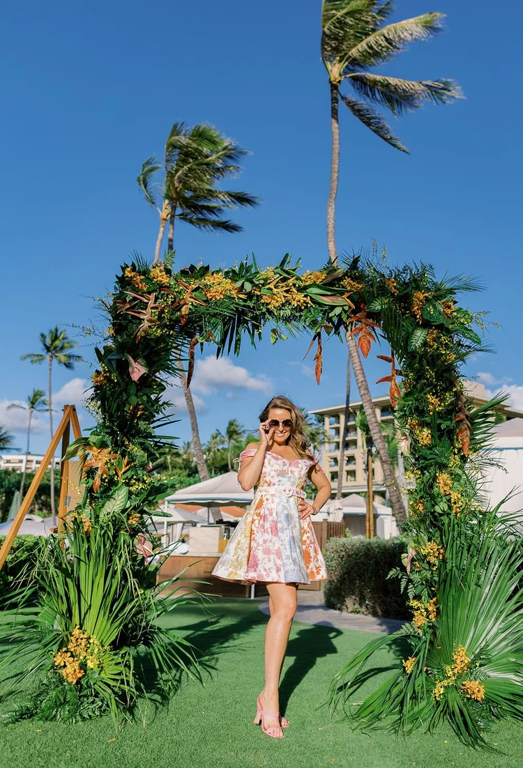 Brianne Garritano under a tropical floral arch at a destination event