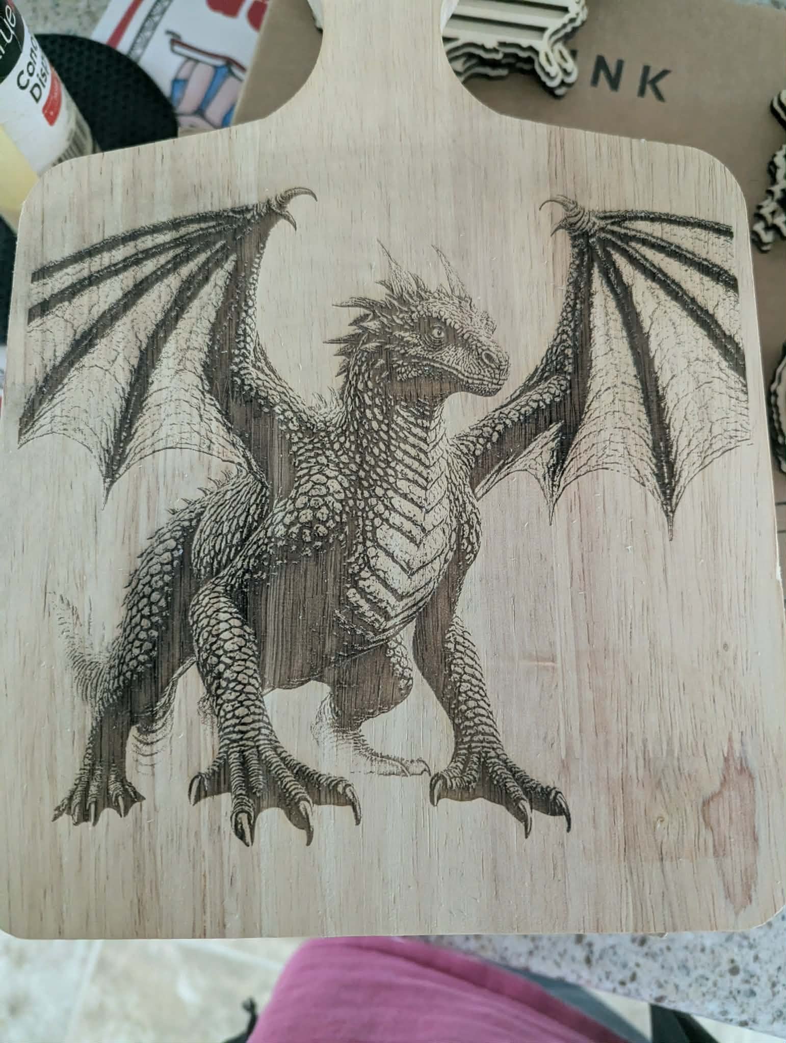 A wooden cutting board engraved with a detailed dragon, wings outstretched