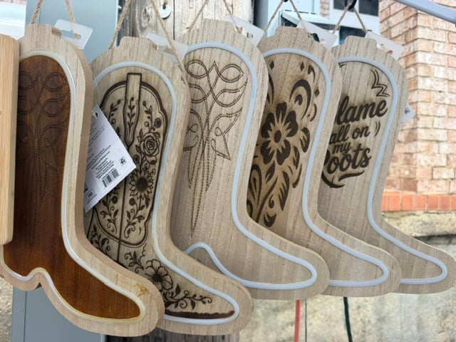 Wooden cowboy boot signs engraved with florals, western stitching, and the phrase blame it all on my roots