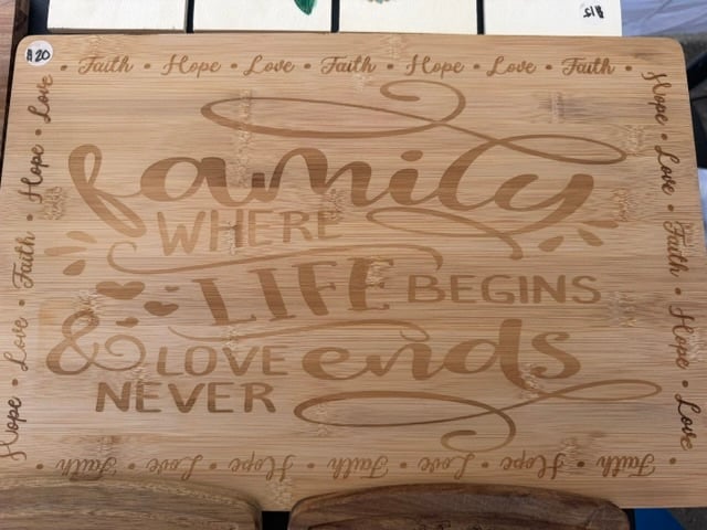 A bamboo cutting board engraved with family, where life begins and love never ends, bordered by faith, hope, and love