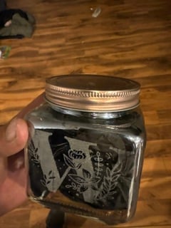 A square glass jar engraved with a floral monogram V