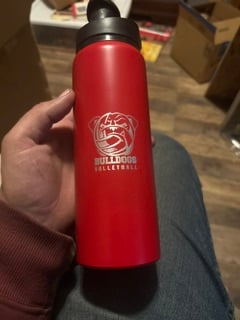 A red insulated water bottle engraved with a Bulldogs volleyball logo