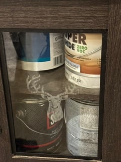 A glass cabinet door panel engraved with a deer head