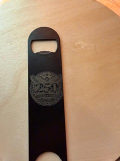A black steel bar bottle opener engraved with a 250th anniversary eagle emblem